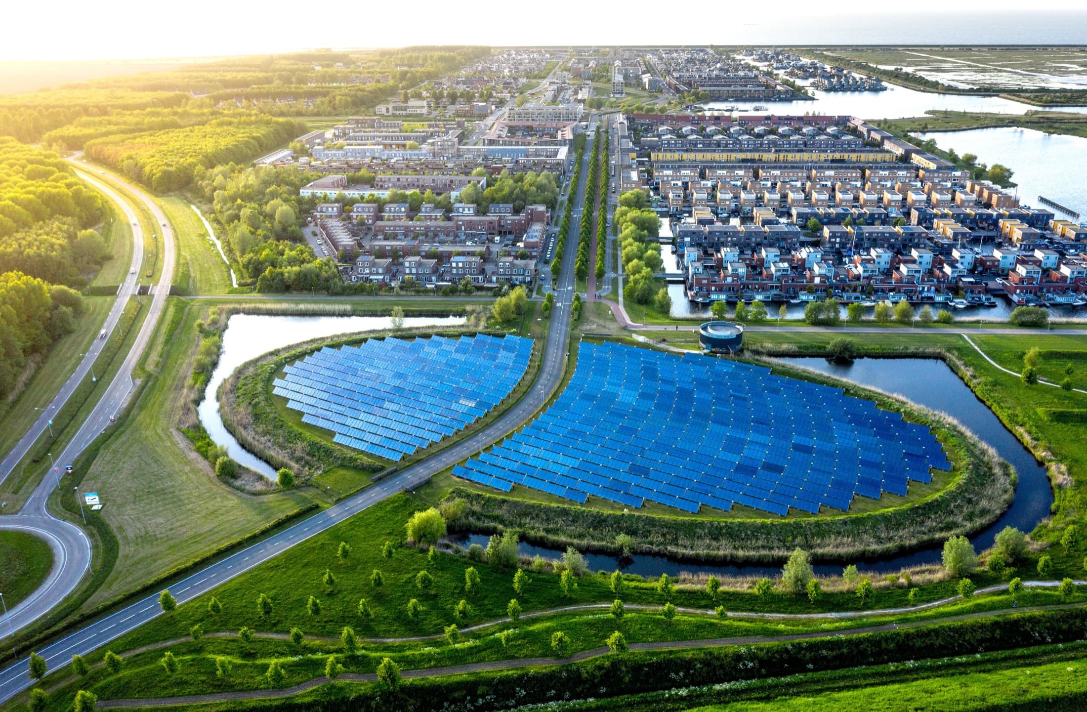 Luchtfoto van een zonnepark tussen een woonwijk en het water